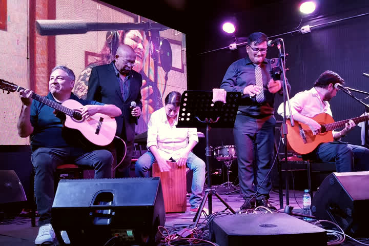 Carlos Mosquera y su grupo con guitarras y cajón sobre el escenario.